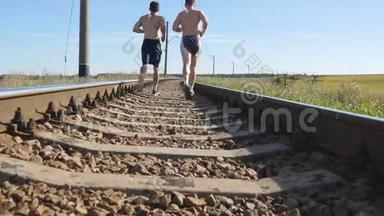 两个人在<strong>铁轨</strong>上的<strong>铁轨</strong>之间奔跑。 在铁路轨枕上慢跑的跑步者。 运动腿